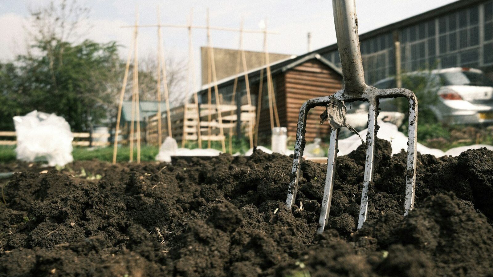 a garden fork stuck in a pile of dirt