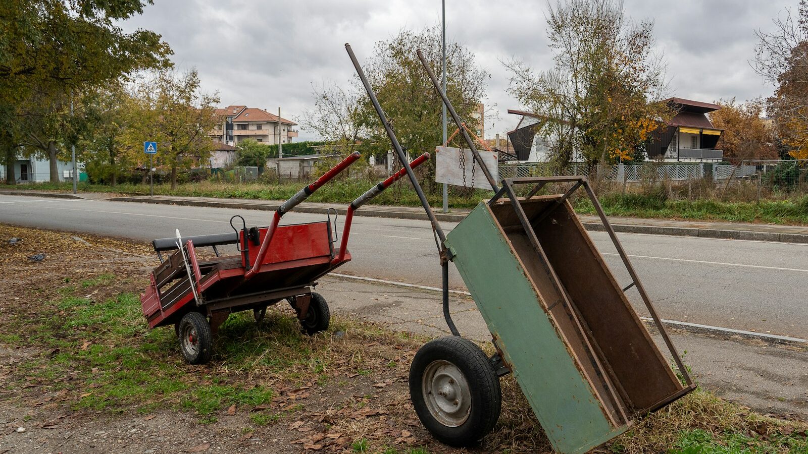 Two old wheelbarrows on grassy roadside.