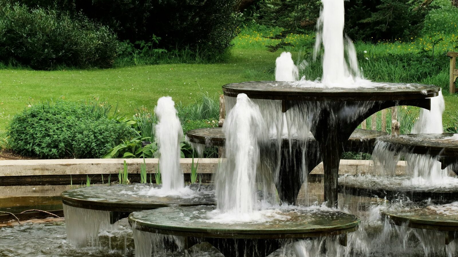 A tiered fountain sprays water in a garden
