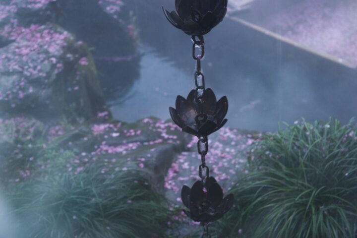 Decorative chain with lotus flower shapes hangs over garden
