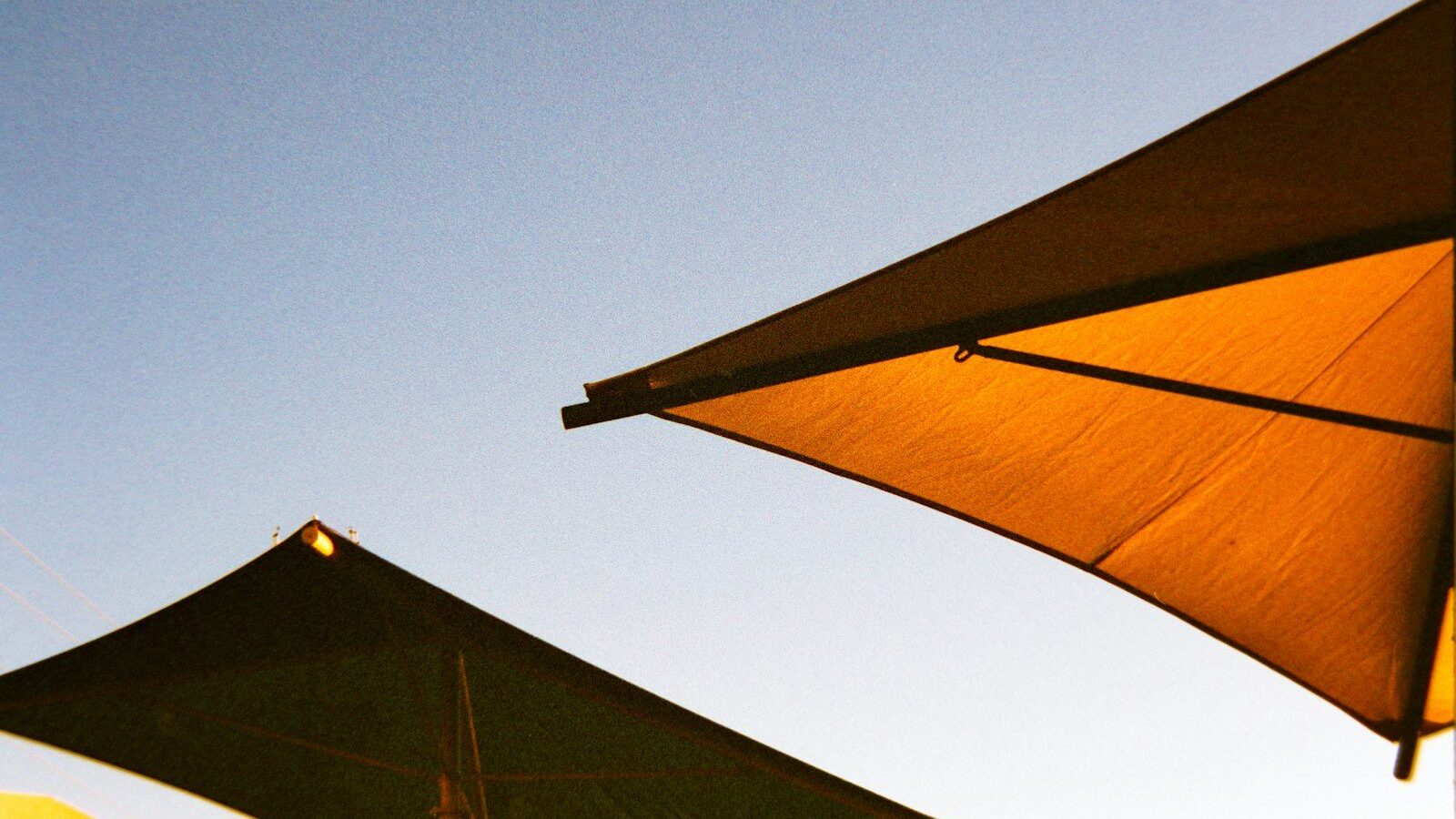 Two large sunshades against a clear blue sky