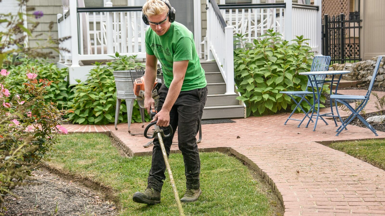 man in green t-shirt and black pants holding black and brown shovel