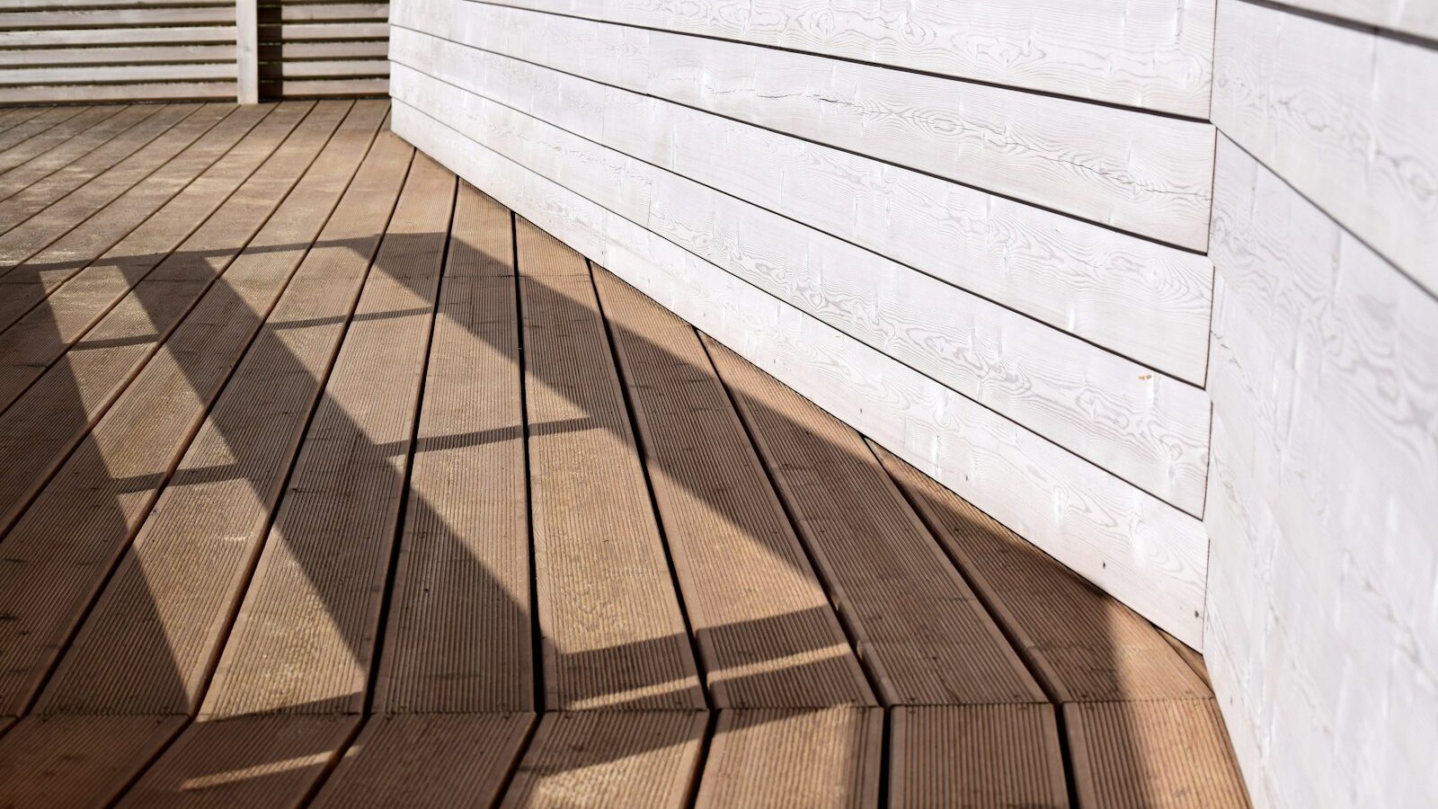 the shadow of a person standing on a wooden deck