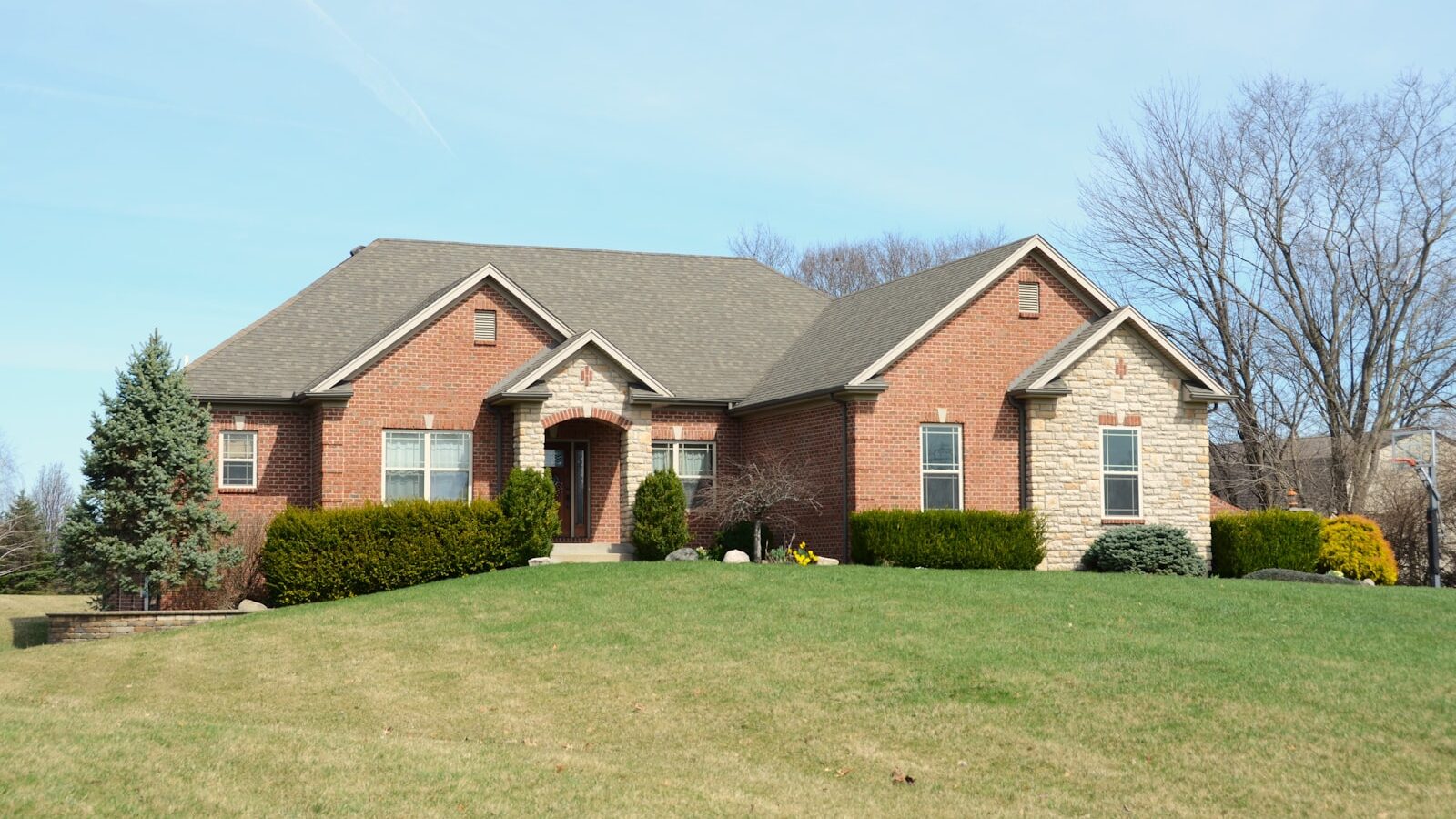 A large brick house with a manicured lawn.