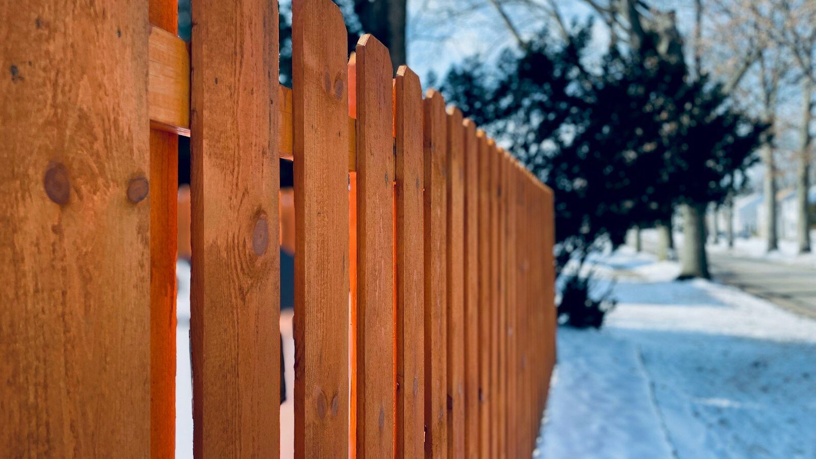 a close up of a wooden fence in the snow