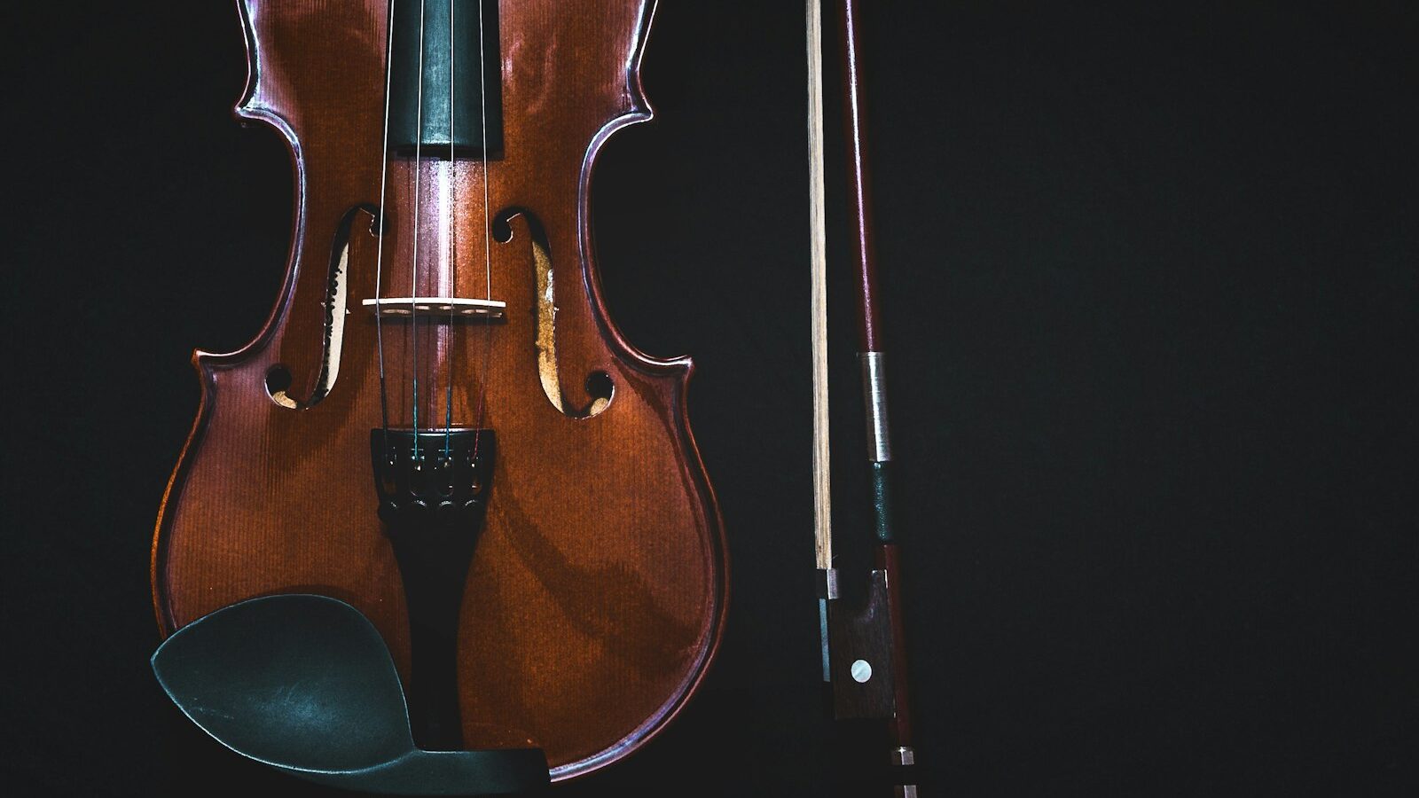brown violin with bow in black background