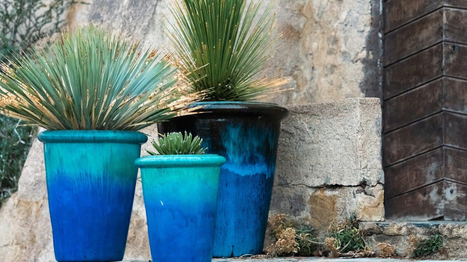 a couple of blue pots sitting on top of a stone wall