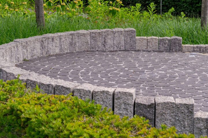 Circular paved patio with low stone wall and green bushes