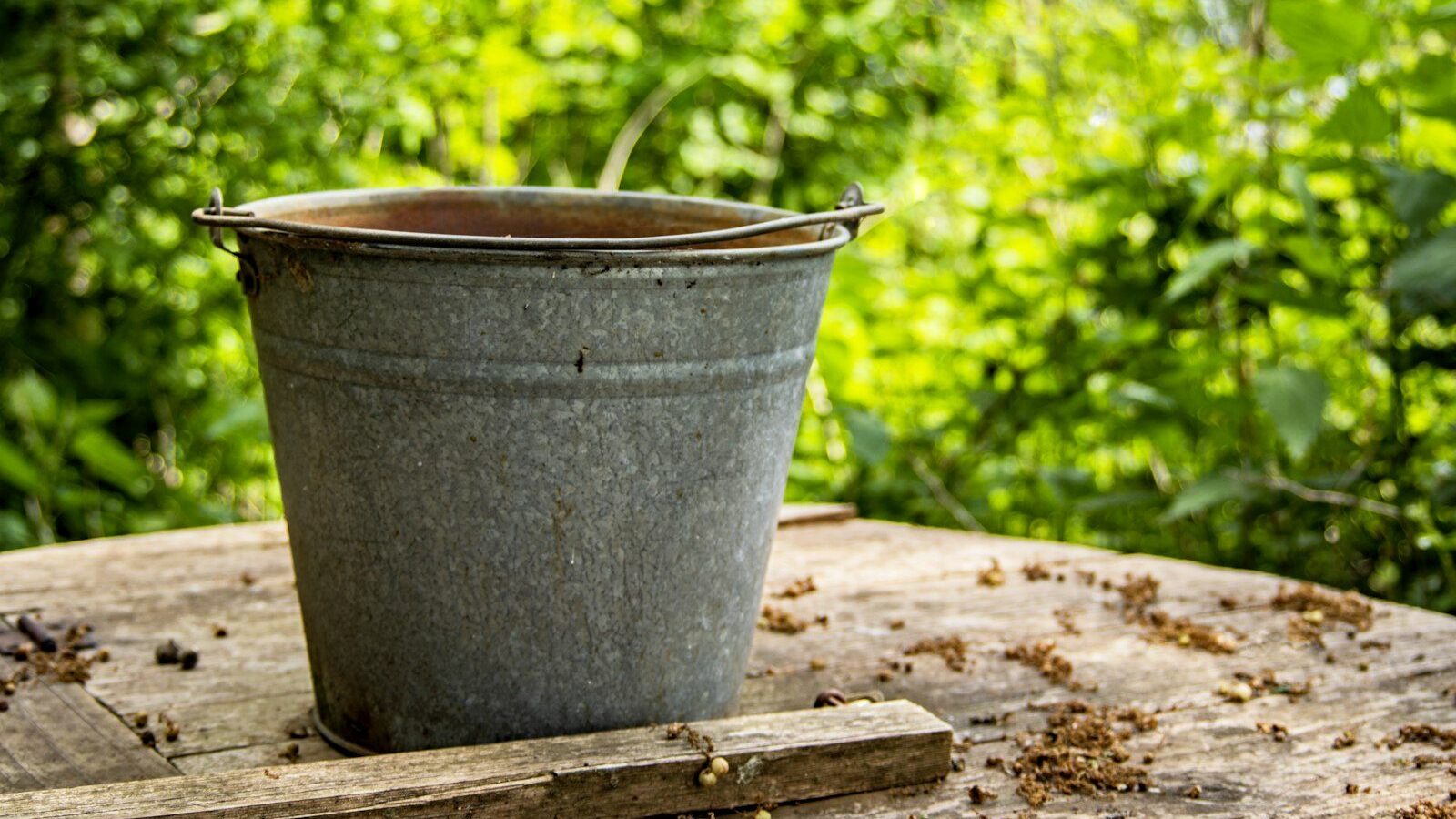 gray steel bucket on brown wooden table
